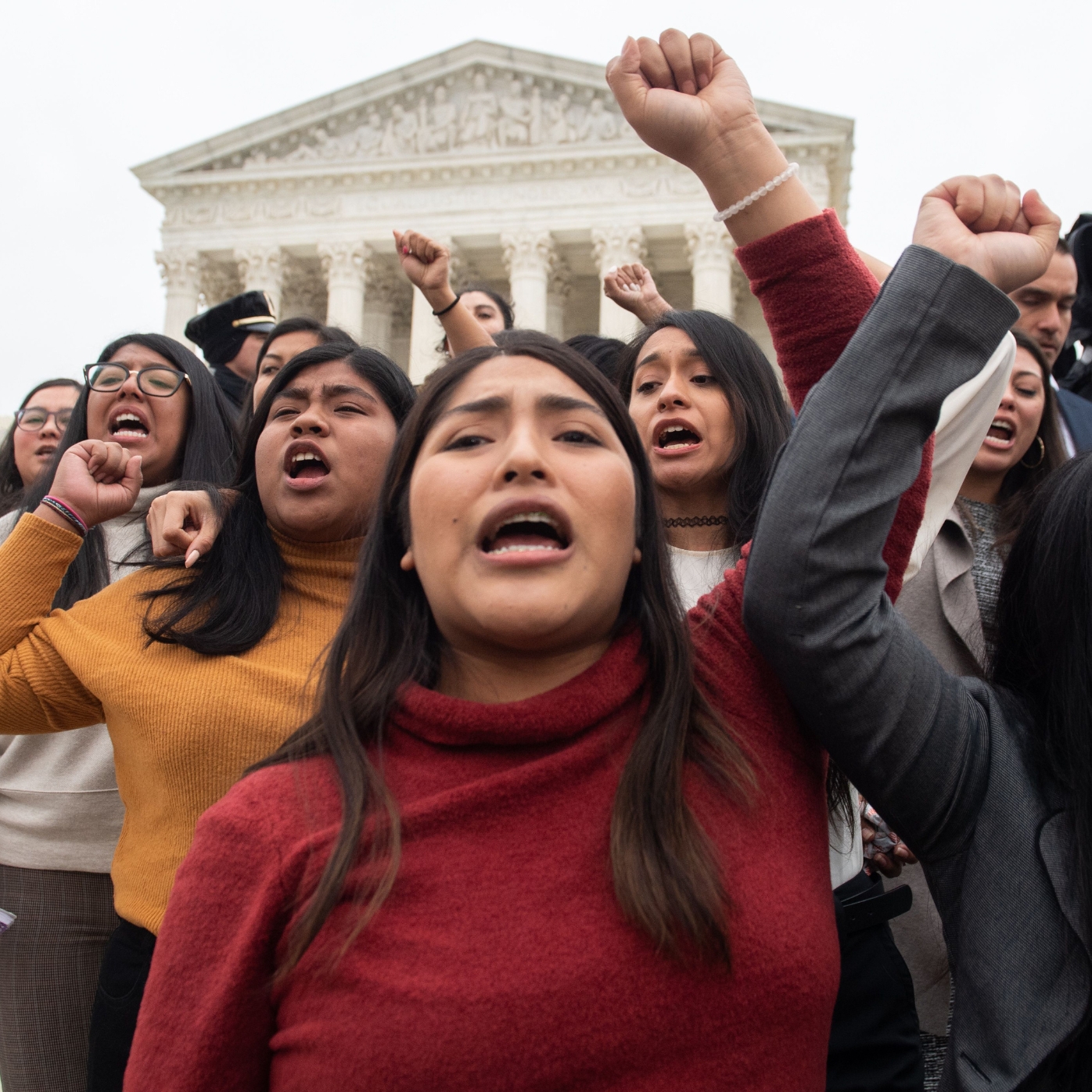 People raise their fists in the air on the steps of the U.S. Supreme Court after attending arguments in a case about the Deferred Action on Childhood Arrivals.