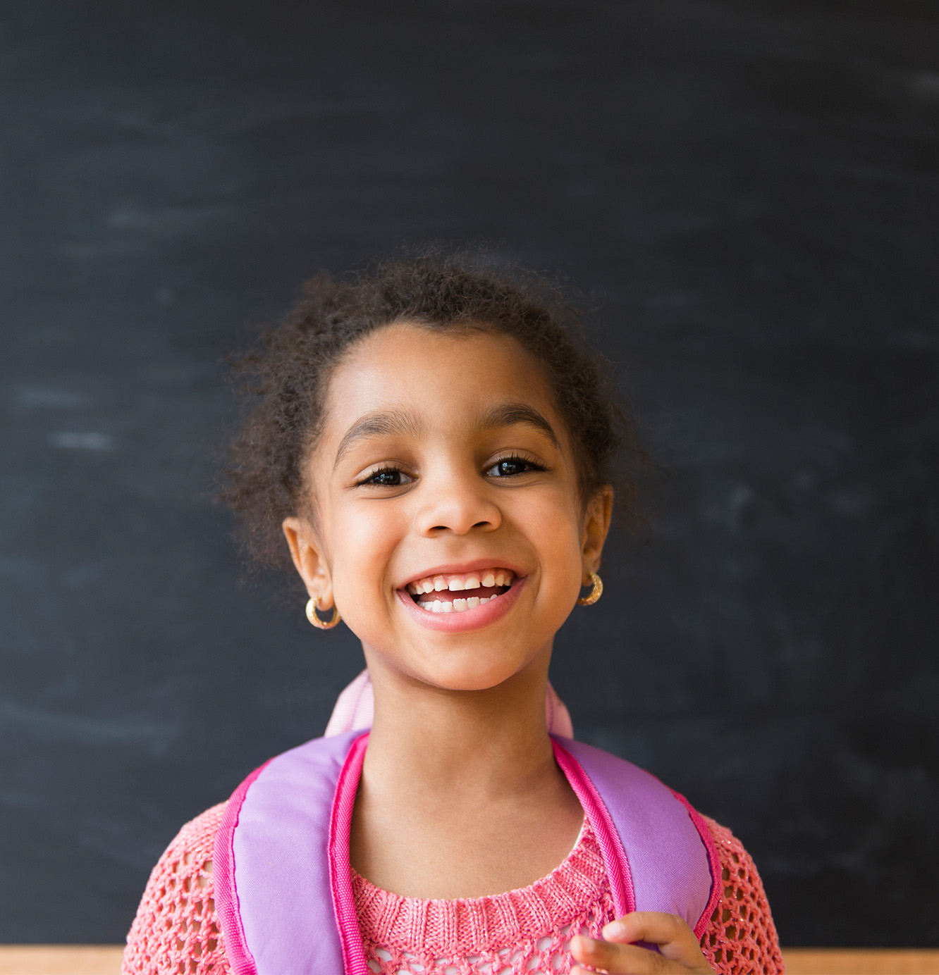 Young student wearing a backpack smiles.